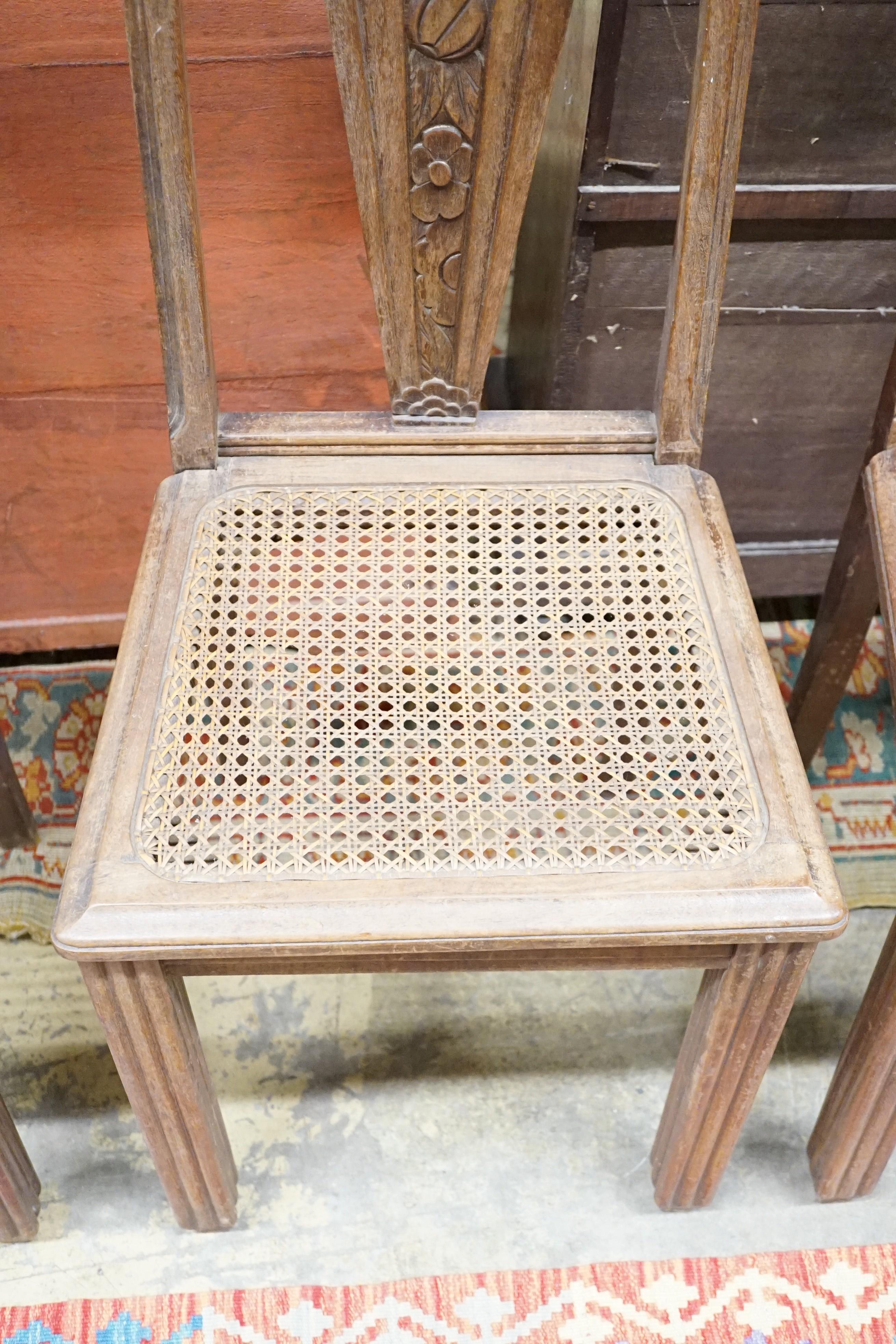 A set of six Continental Art Deco carved and stained beech salon chairs with caned seats, width 44cm, height 96cm